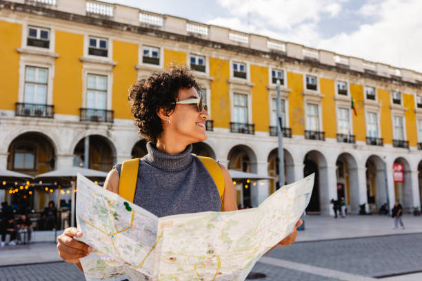 Smiling tourist holding a map, wearing yellow